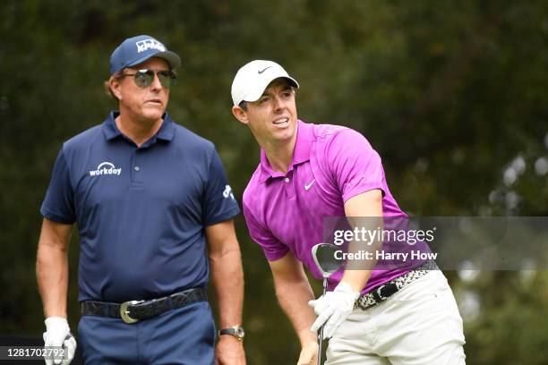 Rory McIlroy of Northern Ireland watches his shot from the sixth tee as Phil Mickelson of the United States looks on during the first round of the...