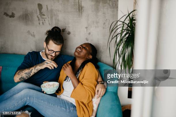 pareja relajante en el sofá en casa viendo la televisión - lovers 2020 film fotografías e imágenes de stock