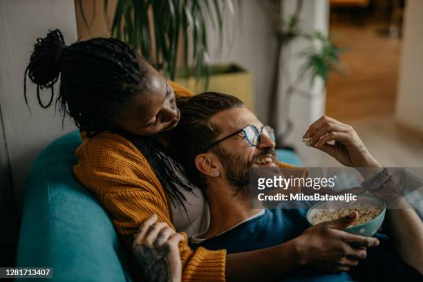 het ontspannen van het paar op de laag thuis lettend op tv - couple on sofa stockfoto's en -beelden