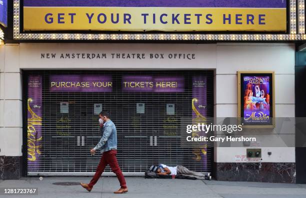 Homeless person sleeps in front of the closed New Amsterdam Theatre that hosts the Broadway play Aladdin on October 22, 2020 in New York City.