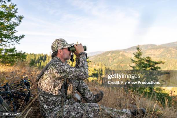 cazador de ballestas usando prismáticos mientras rastrea el alce - hunting fotografías e imágenes de stock