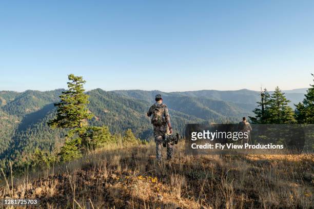 mann jagt wild mit armbrust wandern in den bergen - jäger stock-fotos und bilder