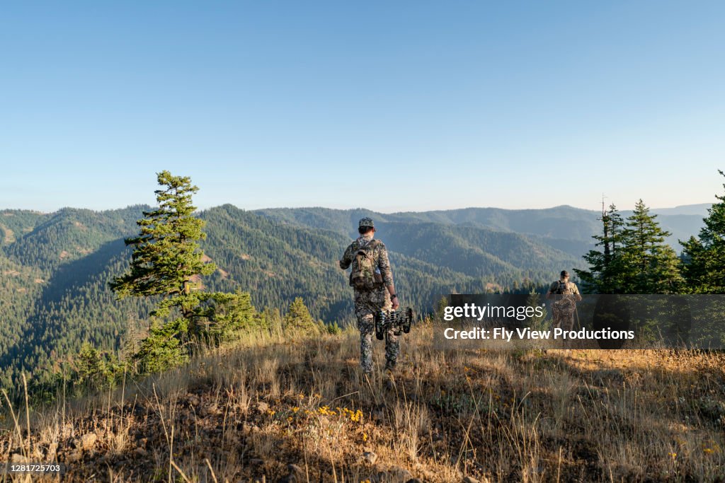 Man hunting wild game with crossbow hiking in mountains