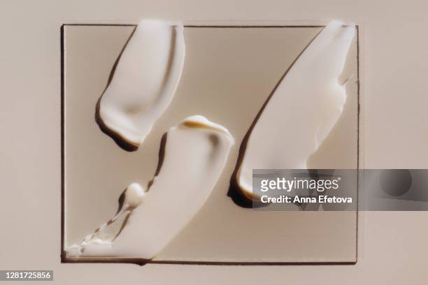 strokes of cream on piece of glass - cremefarbig stock-fotos und bilder