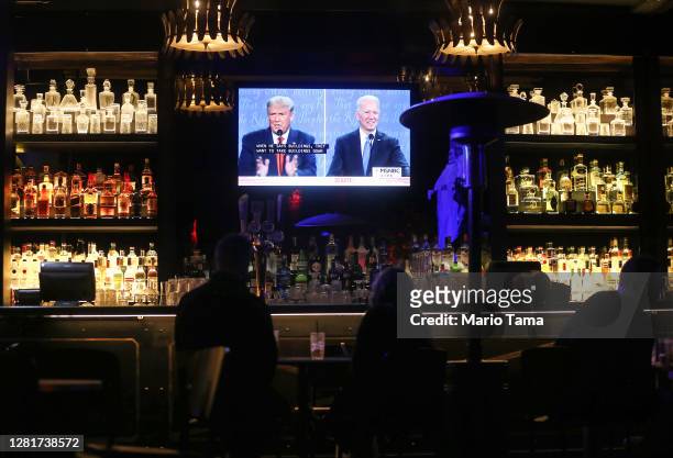 People watch a broadcast of the final debate between President Donald Trump and Democratic presidential nominee Joe Biden at The Abbey, with socially...