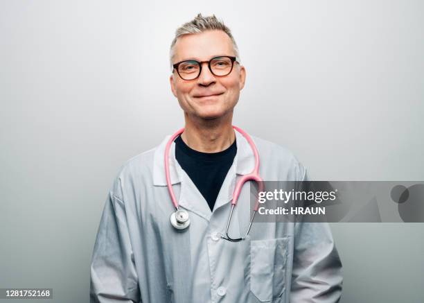 porträt eines lächelnden stattlichen reifen männlichen arzt - handsome doctors stock-fotos und bilder