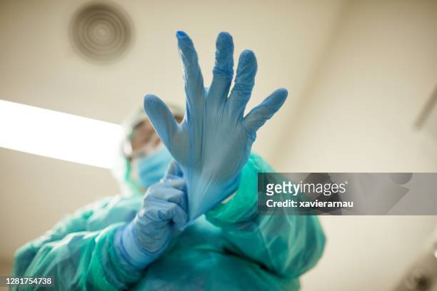 male healthcare worker putting on surgical gloves - hospital safety stock pictures, royalty-free photos & images