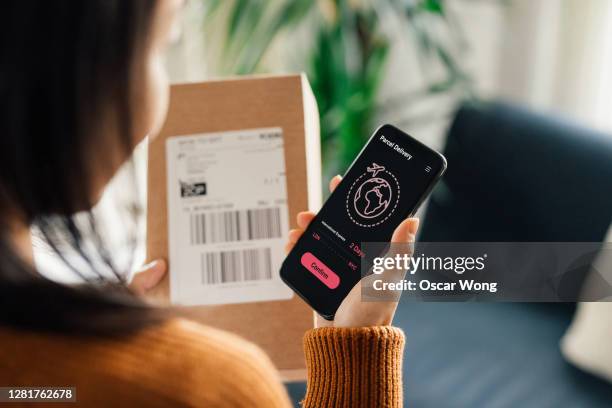 young woman arranging parcel delivery on smart phone - femme de dos smartphone photos et images de collection