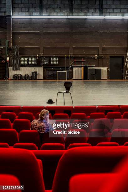 director working on a script in an empty theatre with red chairs and a empty stage - opera backstage stock pictures, royalty-free photos & images