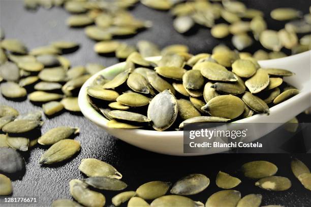 pumpkin seeds on a spoon - semi di zucca foto e immagini stock