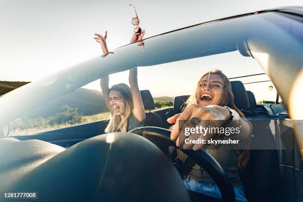 cheerful female friends going on a trip in convertible car. - singing imagens e fotografias de stock