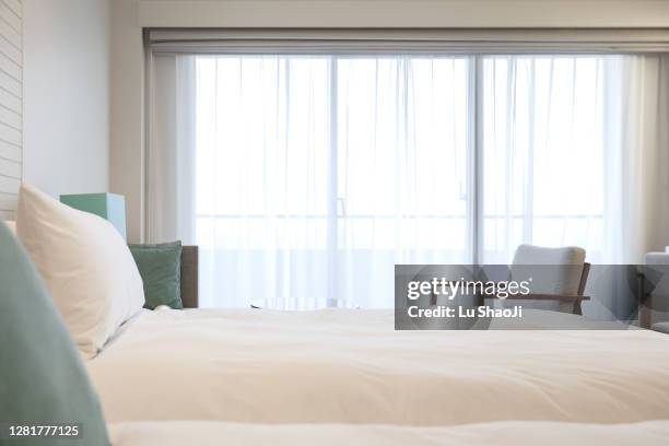 comfortable bed and bright windows - curtain hotel stock-fotos und bilder
