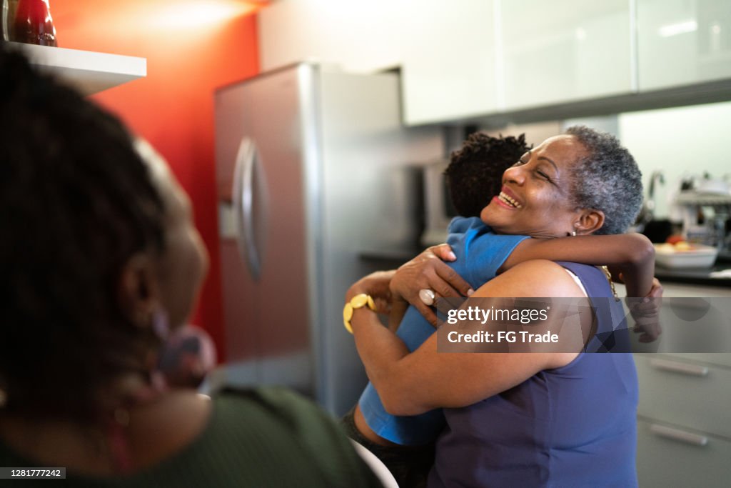 Grandson embracing grandmother at home