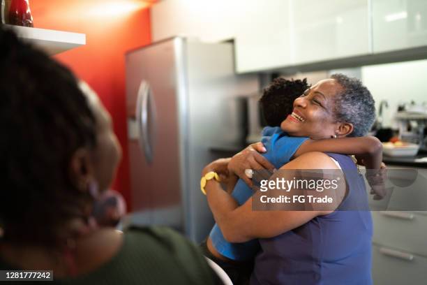 grandson embracing grandmother at home - black family reunion stock pictures, royalty-free photos & images