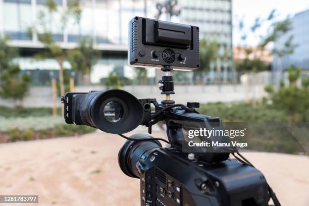 close-up professional video camera with tripod on the street with a building in the background - stock photo - press conference cameras stock pictures, royalty-free photos & images