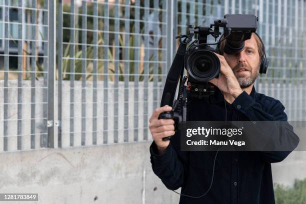 cameraman holding camera over his shoulder looking at camera - stock photo - cameraman photos et images de collection