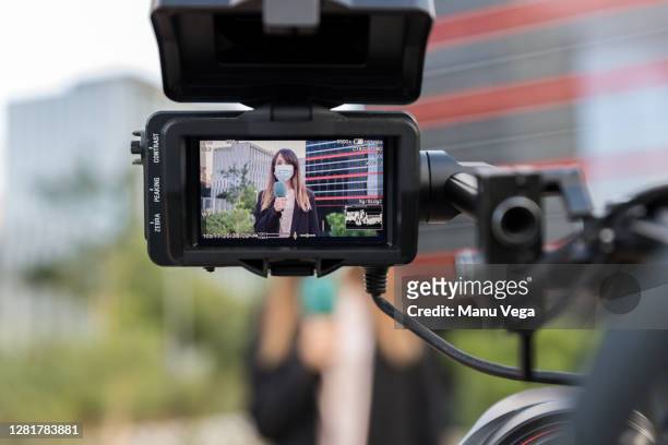 camera broadcasting the news with a journalist wearing a medical mask - stock photo - tv reporter street stock pictures, royalty-free photos & images