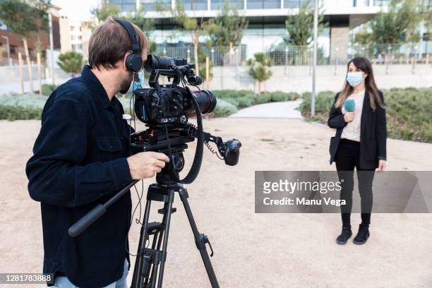 cameraman and journalist wearing medical masks - stock photo - cinematographer imagens e fotografias de stock