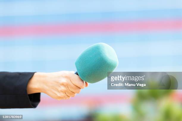 journalist's hand with microphone on color blue holding background - stock photo - interview fotografías e imágenes de stock
