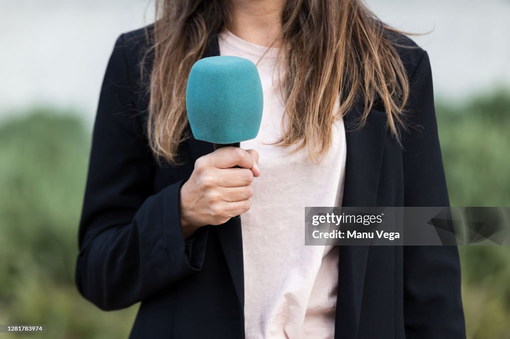 Close-up of journalist woman holding a microphone - stock photo