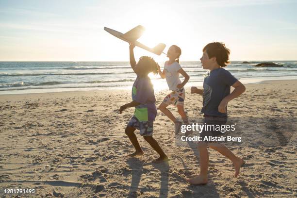 children running along a beach with model plane - menina fantasia bonita imagens e fotografias de stock