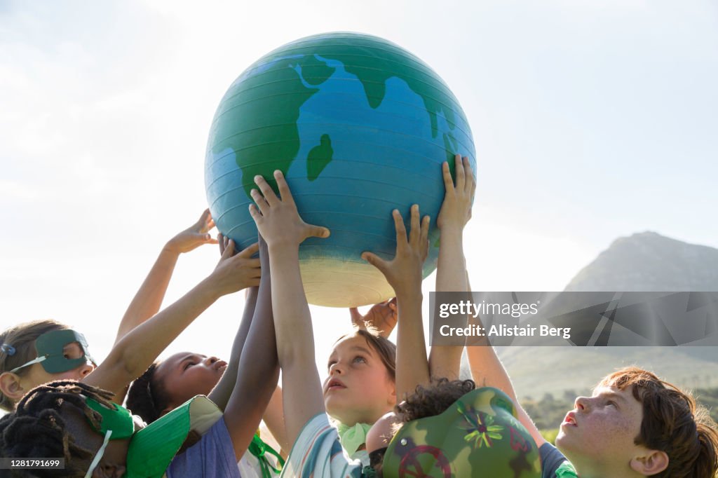 Group of young eco-warriors holding up a large globe