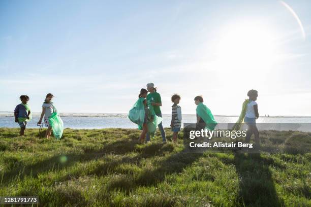 young green activists picking up litter in nature - volunteer beach photos et images de collection