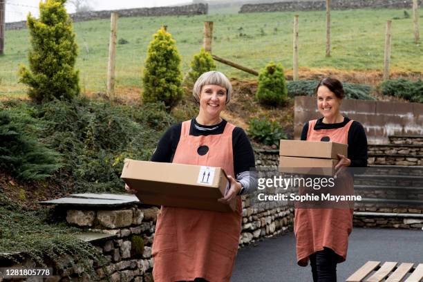 two colleagues at a bakery carrying boxes ready for delivery - femalefocuscollection stock pictures, royalty-free photos & images