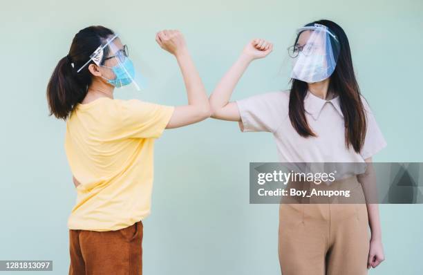 two asian women doing the elbows bump while greeting during covid-19 pandemic situation. - elbow bump stock pictures, royalty-free photos & images