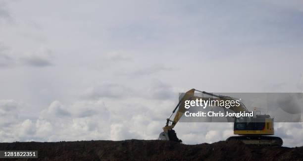 excavator silhouette on pile of earth - vehículo de construcción fotografías e imágenes de stock