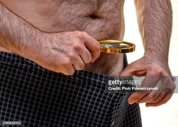 man looking inside his underwear through magnify glass. - genital herpes foto e immagini stock
