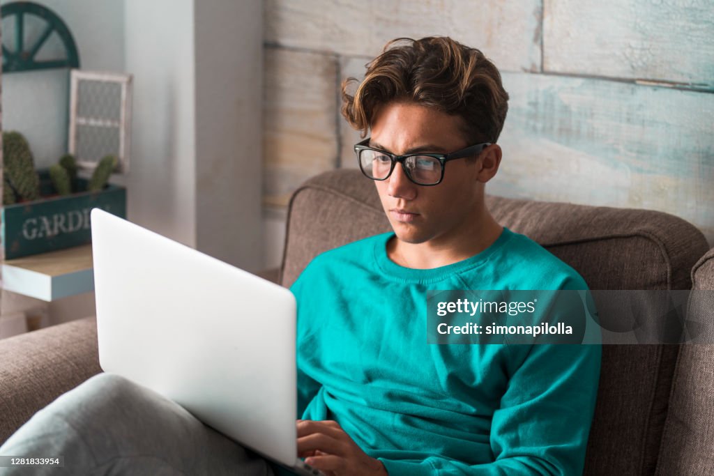 Young student at home in smart working with college classes and lessons use laptop computer - young people with eyeglasses and technology - modern lifestyle with online courses and school
