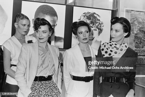 British model and actress Lesley-Anne Down with three other models wearing 70s hairstyles, 28th March 1979. On the right is a poster for the film...