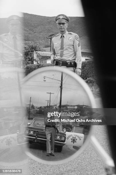 Officers of the California Highway Patrol , one with a shotgun, USA, December 1964.