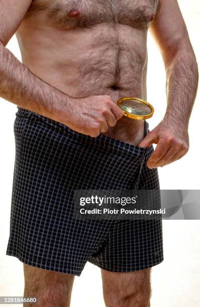 man looking inside his underwear through magnify glass. - genital herpes stock pictures, royalty-free photos & images