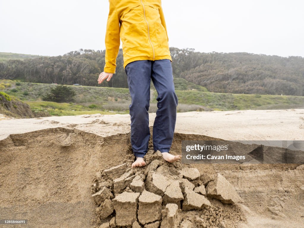 Detail Of Young Person Standing On Crumbling Edge Of Sandy Ledge High ...