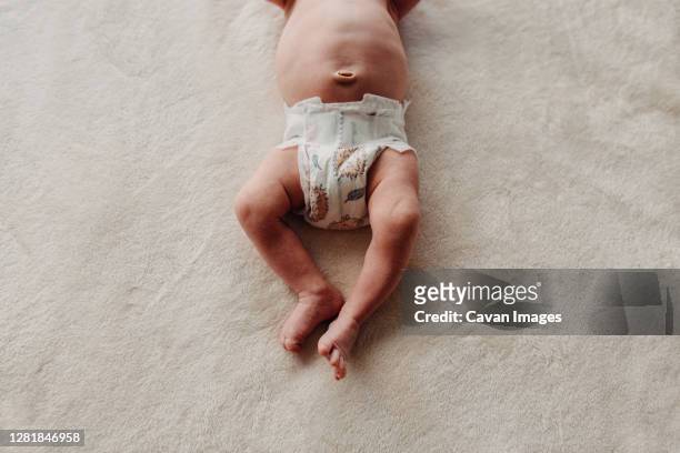 close up of newborn belly button white diaper legs and feet - navel stockfoto's en -beelden