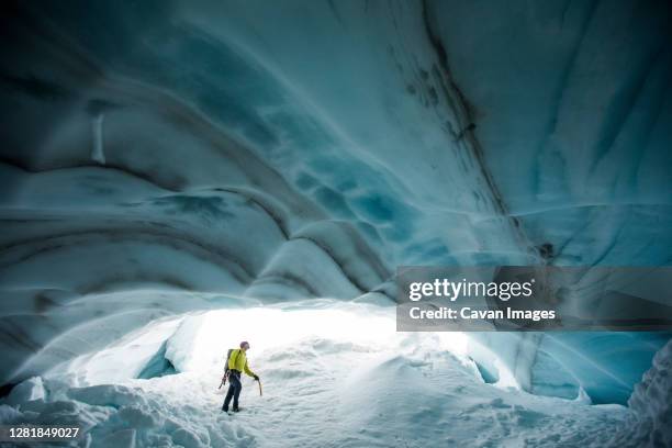 ice climber looks up at the ceiling of a glacial ice cave in canada. - climate scientist stock pictures, royalty-free photos & images