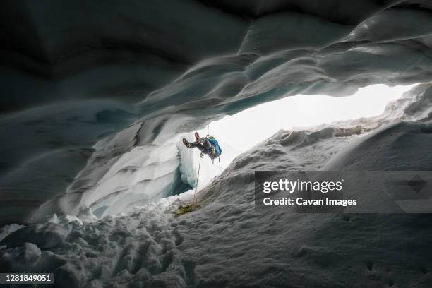 mountain climber rappelling into crevasse / glacial ice cave. - caving stock pictures, royalty-free photos & images