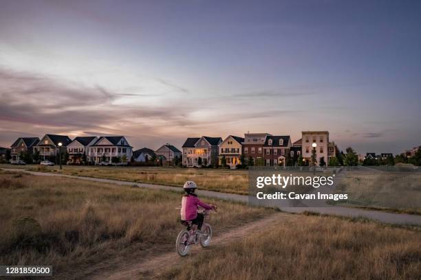 young girl bikes on a park dirt path on the edge of a neighborhood - colorado home stock pictures, royalty-free photos & images