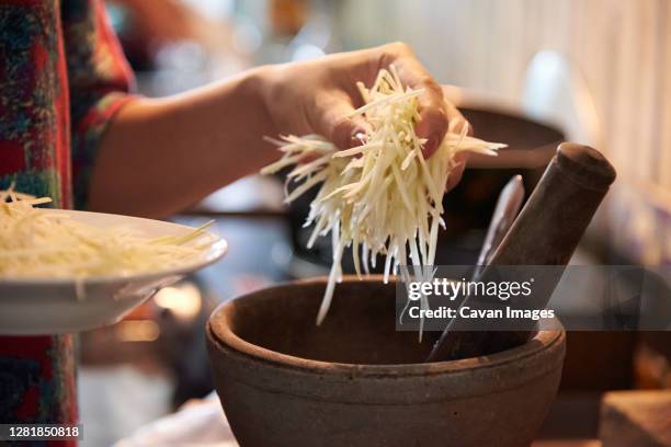 chef putting the sliced green papaya to the mortar - khon kaen stock-fotos und bilder