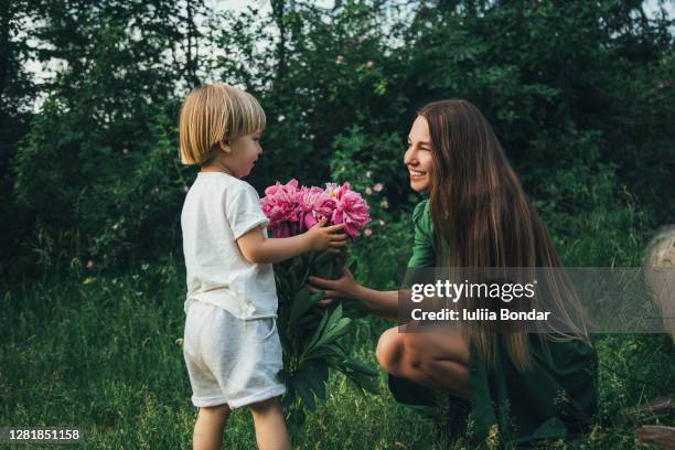 mother and son having fun. son giving flowers to his mother. - giving flowers stock pictures, royalty-free photos & images