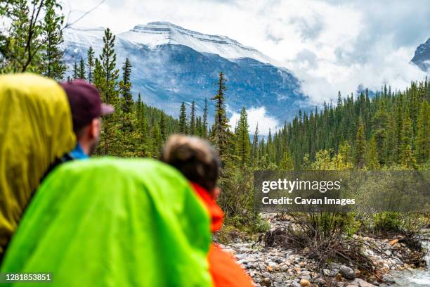 couple observing fresh snow on nearby mountain peak during hike - saskatchewan highway stock pictures, royalty-free photos & images