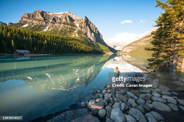 hiker standing at the edge of lake louise in banff national park - lake louise stock pictures, royalty-free photos & images