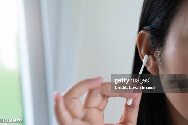 woman cleaning ear with cotton swab. healthcare and ear cleaning - cotton swab ストックフォトと画像