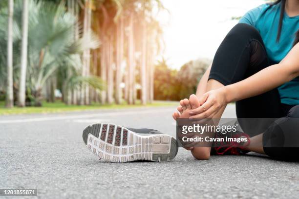 asia woman massaging her painful foot while exercising. running - swollen ankles stock pictures, royalty-free photos & images