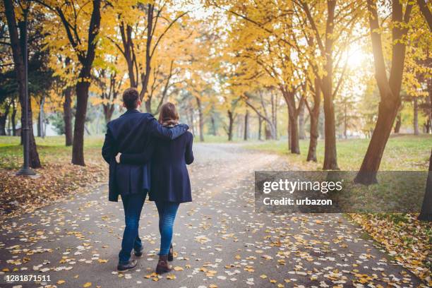 young couple in a park - autumn friends coats stock pictures, royalty-free photos & images