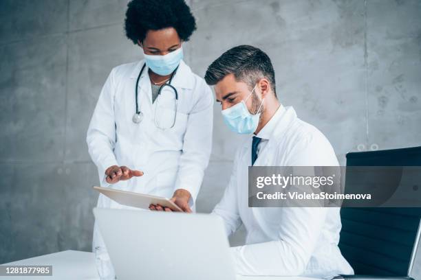 two doctors having conversation over a case in doctor's office. - two masks stock pictures, royalty-free photos & images