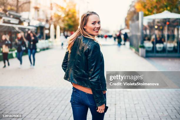 femme gai marchant dans la ville. - regarder par dessus son épaule photos et images de collection