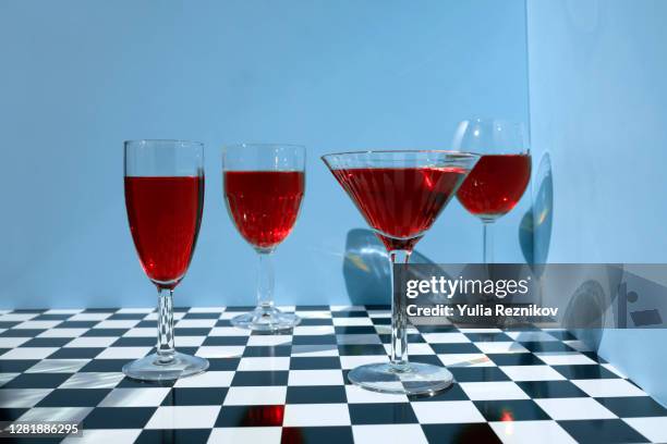 three wine glasses and one martini glass on the blue-chess background - blue martini glasses stock-fotos und bilder